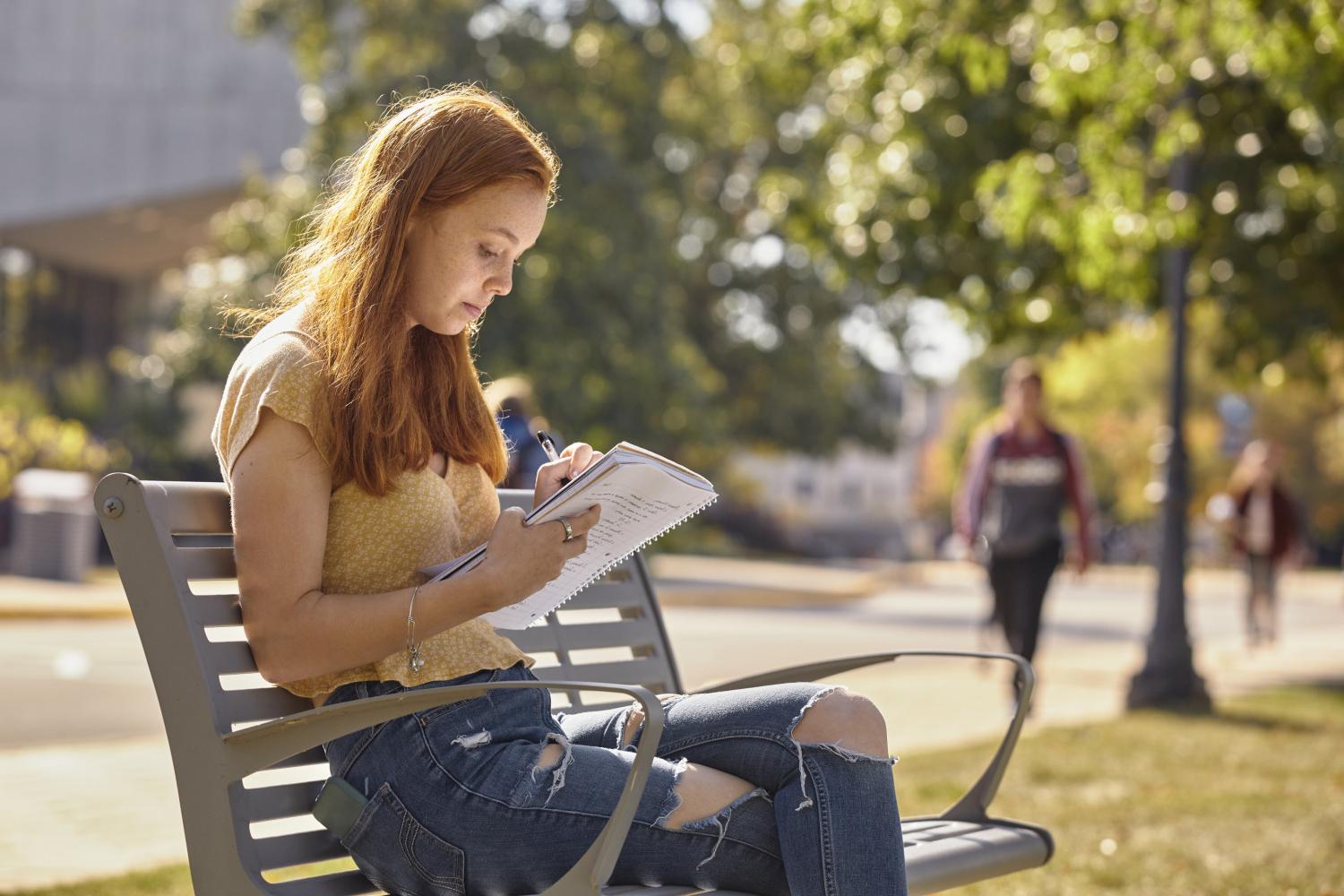 A <a href='http://bmn.mokmingsky.com'>全球十大赌钱排行app</a> student reads on a bench along Campus Drive.